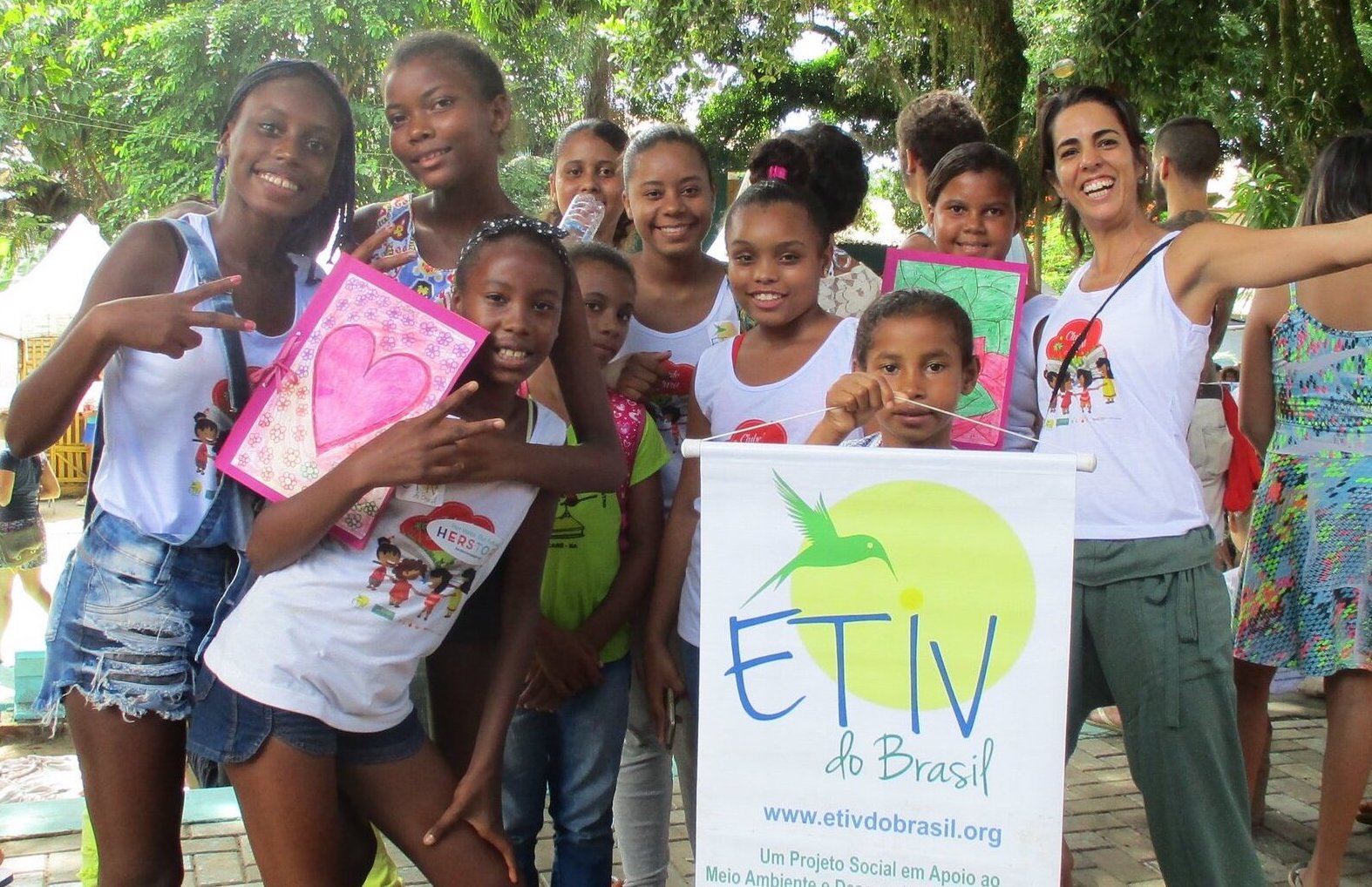 Group of young smiling Brazilian children holding drawings and an "ETIV do Brasil" poster. 