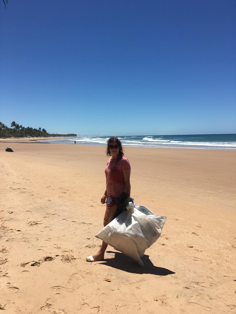Volunteer collecting crude oil in front of beautiful beach